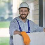 portrait of handsome young male builder in hard hat looking positive